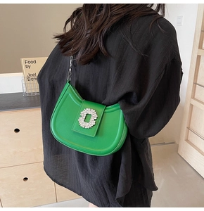 Green crescent shoulder bag with rhinestone buckle and chain strap shown on a model