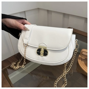 Detail of white saddle bag with T-shaped metal buckle and gold chain strap close-up