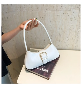 Detail view of a white leather underarm bag featuring a large decorative gold square buckle