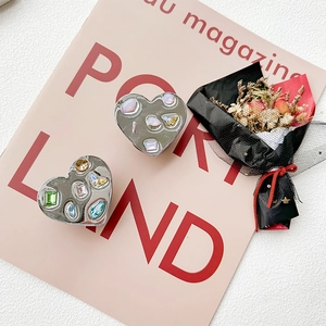 Detail of heart-shaped phone grips with colorful rhinestones on a soft pink magazine