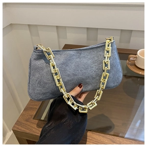 Dettaglio della borsa baguette in pelle scamosciata blu con grossa catena dorata al bar