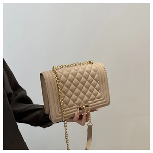 Detail of classic quilted rhombic texture and gold chain on beige crossbody bag