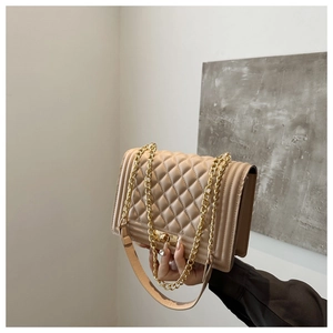 Detailed close-up of quilted beige leather bag with gold metal clasp and accordion sides