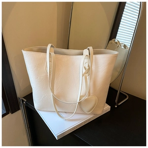 Detail of cream tote bag with pleated leather texture and heart-shaped pendant charm