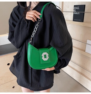 Detail of emerald green hobo bag featuring glossy leather and ornate rhinestone buckle