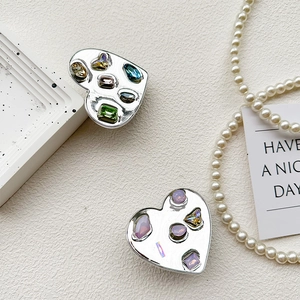Macro shot of silver heart phone grips featuring colorful inlaid gemstones and crystals