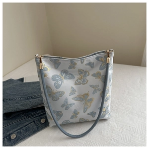 Details der Gold-Schmetterlingsstickerei und blauen Riemen an einer weißen Stofftasche