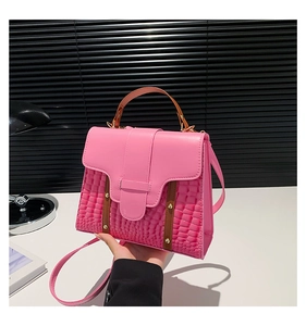 Detailed view of pink crocodile embossed texture and gold rivet studs on a handbag
