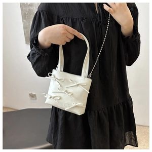 Close-up of white mini tote bag with five 3D bows and a silver metal bead chain strap