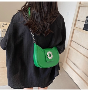Detail of green crescent shoulder bag with large crystal buckle and silver chain