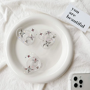 Three heart-shaped glitter phone grips with colorful star rhinestones on a white plate