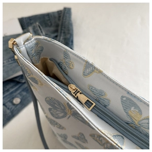 Detail der hellblauen Jacquard-Schultertasche mit goldener Schmetterlingsstickerei