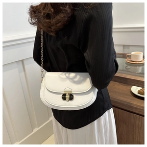 Chic white leather saddle bag with gold chain strap on model in cozy cafe setting