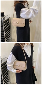 Close-up of minimalist beige shoulder bag with gold metal buckle and textured leather detail