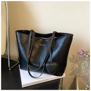 Close-up of black pleated tote bag with heart charm and white Huanikou script logo