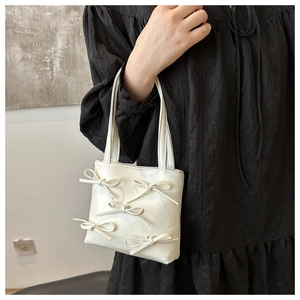 Close-up of white bucket bag featuring 3D bow details and soft matte leather texture
