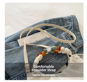 Detail of white pleated cloud bag with multi-colored beaded handle and adjustable strap