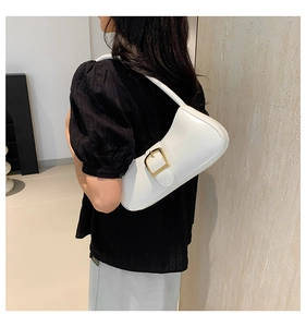 Detailed close-up of glossy white patent leather underarm bag with gold metal buckle decoration