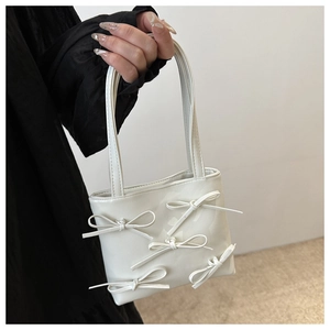 Detail of white mini bow handbag with high-quality leather texture and sleek handle design