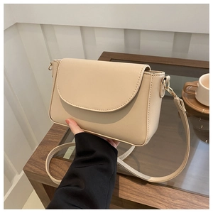 Detail view of cream beige crossbody bag with matte leather texture and gold D-ring hardware