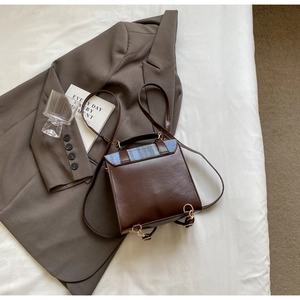 Detail of dark brown leather backpack with blue plaid accent and gold metal hardware