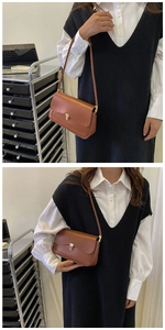 Detailed view of brown leather bag featuring an irregular gold metal buckle and flap