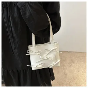 Detail of white PU leather handbag featuring five 3D bows and slim shoulder straps