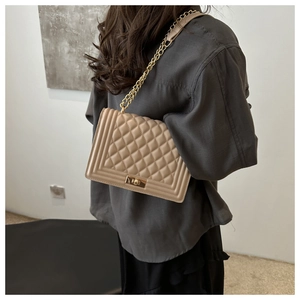 Detail of beige quilted leather chain bag with vintage metal lock on female model