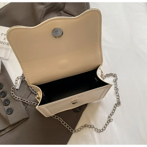 Detail of cream crossbody bag with silver chain strap and magnetic snap closure