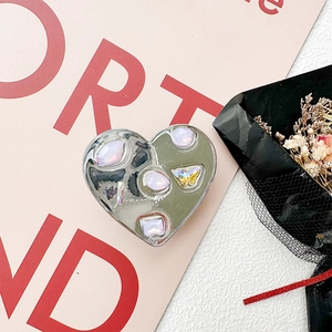 Macro view of heart-shaped silver phone grip with inlaid pink rhinestones and a gold butterfly