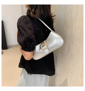 Detail of silver metallic shoulder bag with gold buckle on blue and black outfit