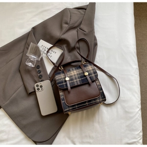 Detailed top view of British style plaid backpack with brown faux leather and metal buckles