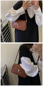 Close-up of brown leather shoulder bag featuring a gold metal buckle and stitching