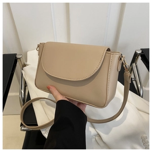 Close-up of beige leather crossbody bag with rounded flap and fine stitching detail