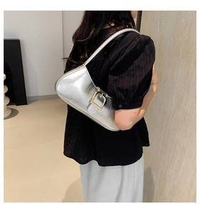 Detail of silver metallic baguette bag featuring a large square buckle and crinkle texture
