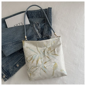 Detail der Bambusblatt-Stickerei auf einer weißen Jacquard-Schultertasche aus Stoff