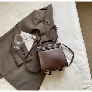 Detail of British style dark brown faux leather backpack with plaid fabric flap and handle