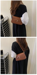 Close-up of brown faux leather shoulder bag with chic gold clasp and slim strap