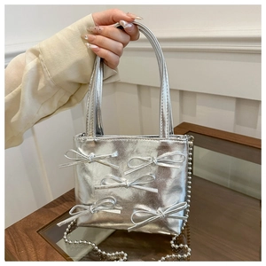 Silver bow accent crossbody bag with metallic finish and sphere chain detail close-up