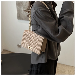 Detail of beige quilted shoulder bag with gold clasp and metal chain leather strap