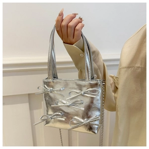 Close-up of silver mini tote bag with metallic bow accents and beaded chain strap
