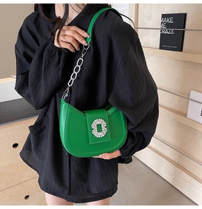 Detail of bright green hobo bag with oversized rhinestone buckle and silver chain strap