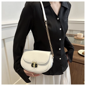 Detail of white half-moon saddle bag with gold metal chain and round twist lock clasp