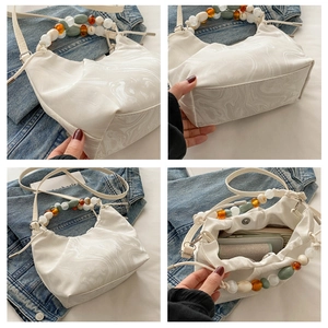 Detail view of marble print cloud bag featuring colorful beaded handle and magnetic closure