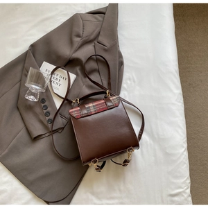 Detail of vintage dark brown leather backpack with green plaid pattern and gold metal buckle