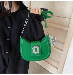 Detailed view of green crescent shoulder bag with silver rhinestone buckle and chain
