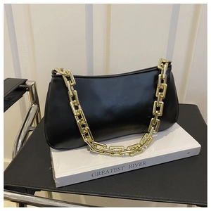 Détail du sac sous le bras en cuir mat noir avec une grosse bandoulière chaîne dorée