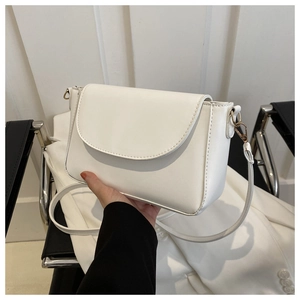 Close-up of a white leather crossbody bag showing fine texture and golden buckles
