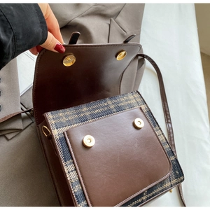 Detail of vintage brown plaid backpack with dual golden magnetic snaps and leather straps