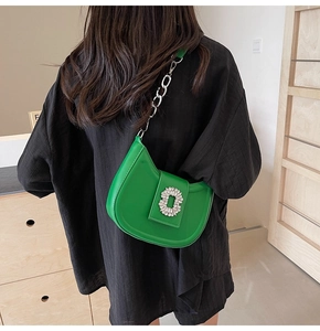 Macro shot of bright green leather crescent bag featuring a luxury crystal square buckle
